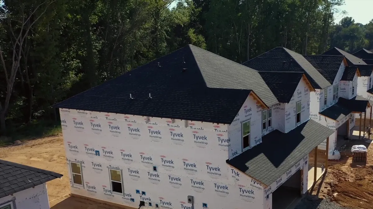 A new home in house wrap, its roofline seen from above