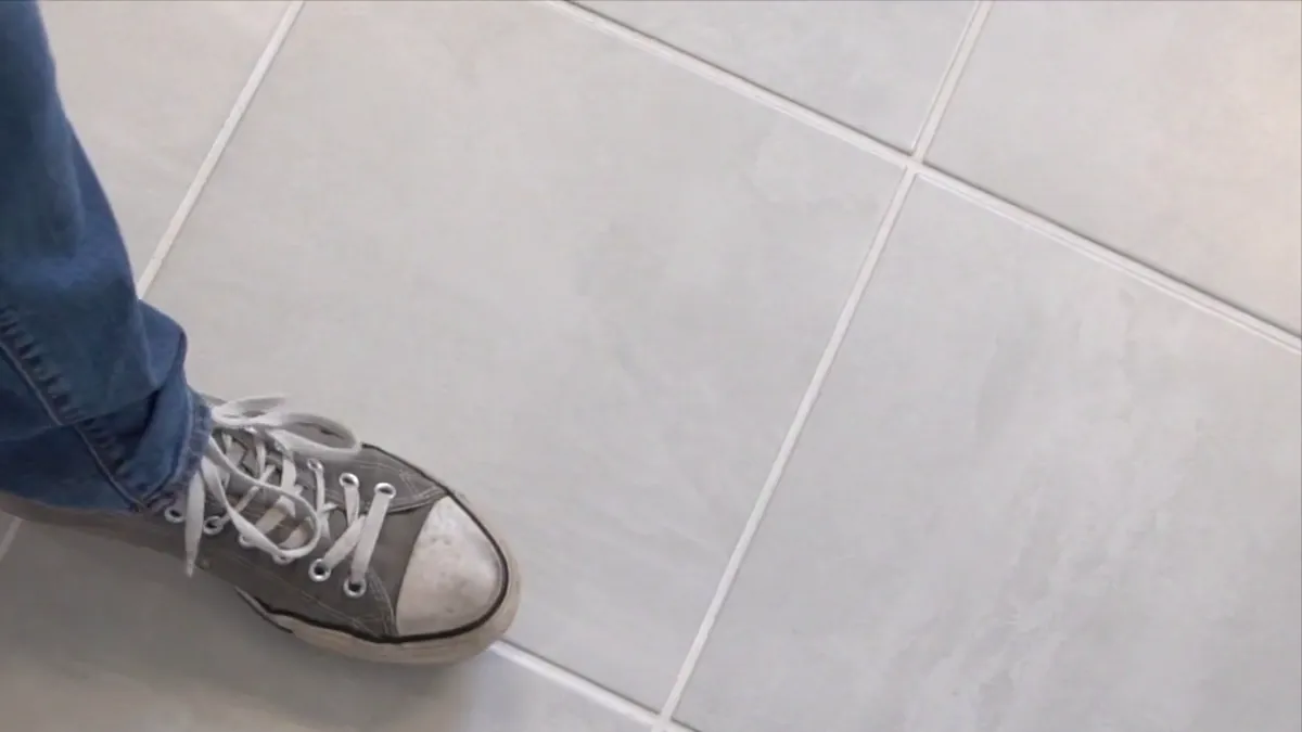 A sneaker mid-step on a finished tile floor